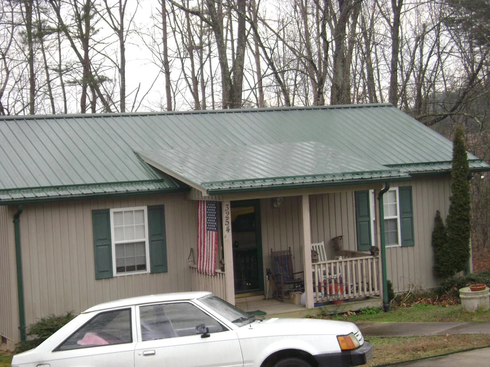 Green metal roof and front porch on a tan sided cottage in Madison